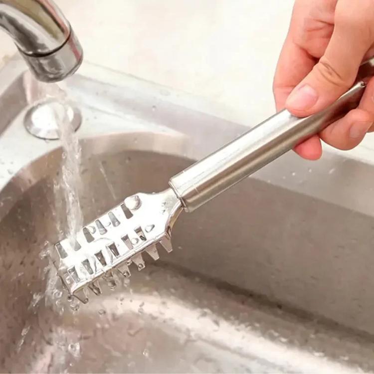 Stainless steel fish scaler rinsed in a sink with water, showing scraper head