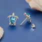Silver-tone turtle stud earrings with blue gemstone and curled clasp backings