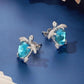 Silver-tone turtle stud earrings with blue gemstone, textured border and hinged backs