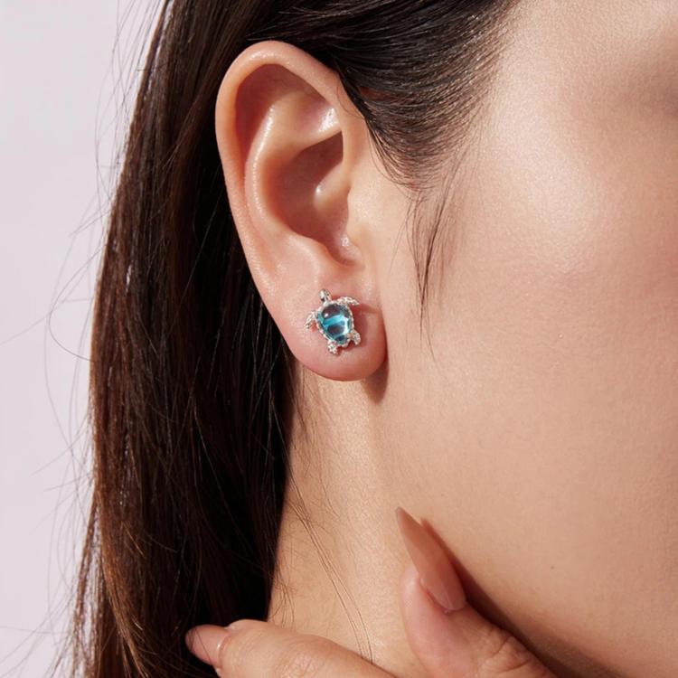 Turtle stud earrings on ear: silver-tone with blue gemstone center