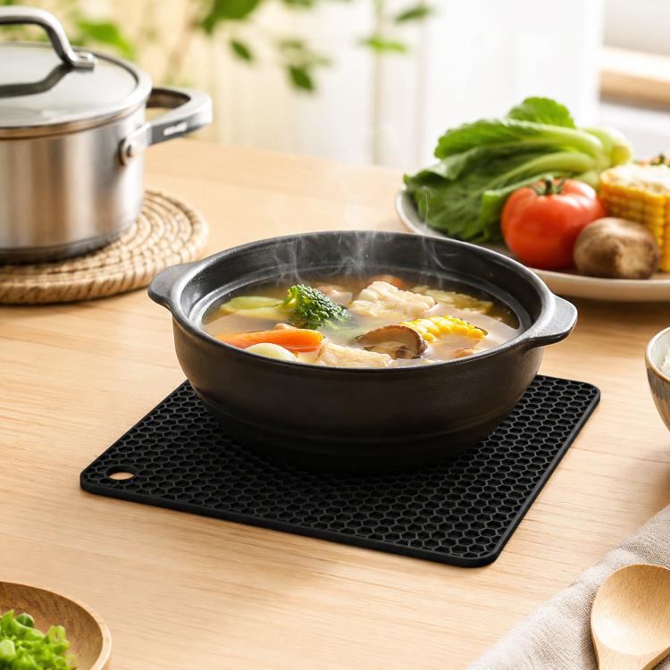 Black square silicone honeycomb table mat coaster under a hot pot