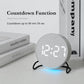 Round LED desk clock with gray fabric face, countdown time shown with blue ambient glow