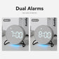 Round LED desk clock showing two alarm times, gray fabric face with blue base light