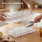 Clear ice freezer tray with lids as hands scoop ice into the compartments