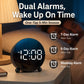 Circular LED alarm clock on bedside, black frame with blue LED digits and PM indicator