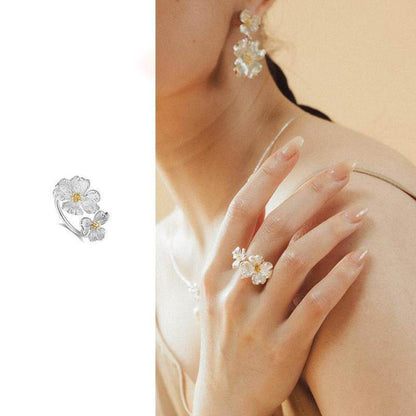 Adjustable open silver-tone dogwood floral ring with two-tone petals and gold center on finger