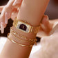 Gold womens vintage quartz wristwatch with dark geometric dial and metal bracelet on wrist