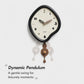 Black irregular pendulum wall clock with cream dial and bronze-brown pendulum weights