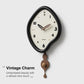 Black irregular pendulum wall clock with cream dial and bronze-brown pendulum weights