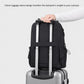 Black backpack with luggage pass-through strap for rolling suitcase handles.