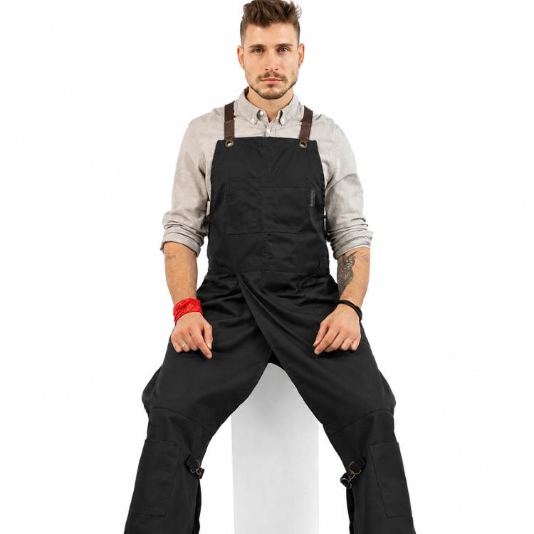Black canvas split-leg work apron with cross-back straps and side utility pockets.