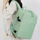 Mint green travel backpack being carried with shoulder straps and top handle