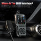 Black OBD2 scanner held near car interior console with attached cable