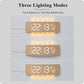 Curved digital LED wall clock in wood finish with warm ambient light from top and bottom