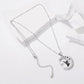 Silver-tone necklace with round moon-cat pendant, long chain, and small dangling charm