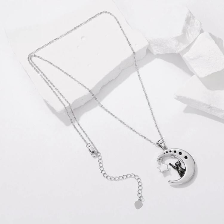 Silver-tone necklace with round moon-cat pendant, long chain, and small dangling charm