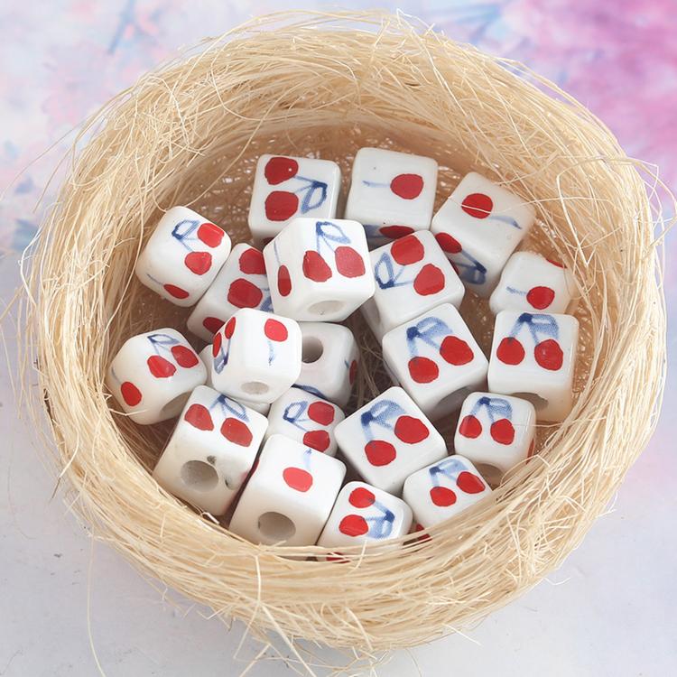 Cherry-pattern square ceramic beads in a nest, large-hole DIY jewelry accessory pack.