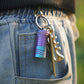 Mini rechargeable LED keychain flashlight clipped to jeans pocket with keyring and keys