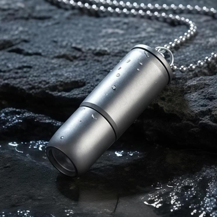 Mini metallic silver flashlight with keychain ring, cylindrical titanium-style body