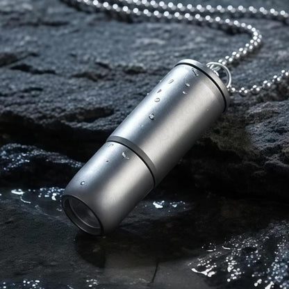 Mini metallic silver flashlight with keychain ring, cylindrical titanium-style body