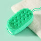 Green oval silicone body scrubber with small bristle tips on a bath sponge backing.