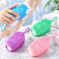 Assorted color silicone bath scrubbers with lanyards shown on a shower surface with foam.
