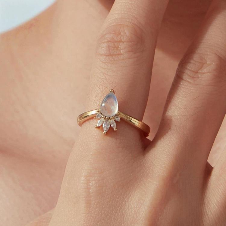 Teardrop moonstone adjustable open ring on finger, gold-tone band with crystal crown