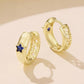 Gold-tone hoop earrings with blue star enamel and textured outer edge
