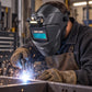 Worker wearing dark auto-darkening welding helmet with integrated headlamp while welding.