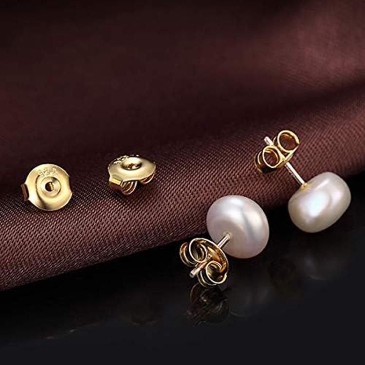 Earring posts with gold earring backs and pearl-style dangles on fabric