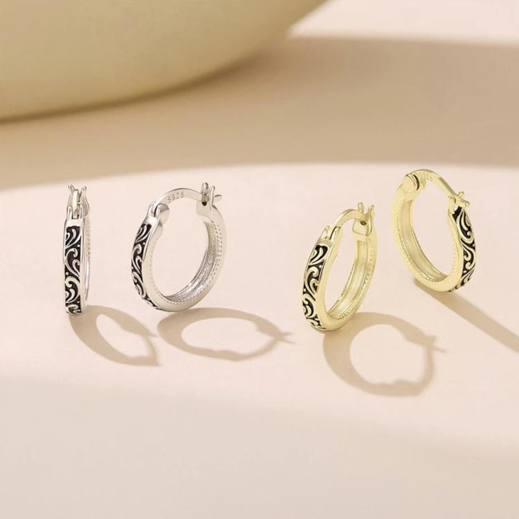 Silver- and gold-tone hoop earrings with vintage scroll pattern, side view