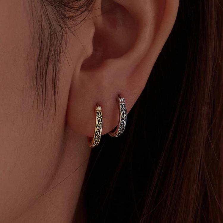 Hoop earrings worn on ear: gold- and silver-tone vintage scroll patterns