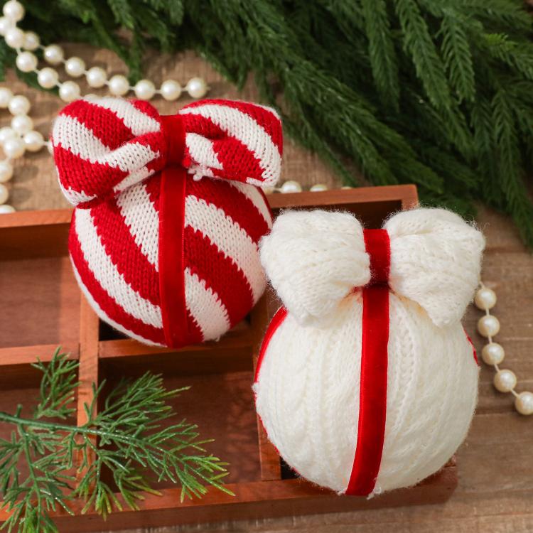 Two knitted bow ornaments—striped red-and-white and white—with hanging red cords