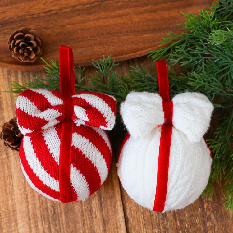 Striped red-and-white and white knitted bow ornaments with hanging red cords