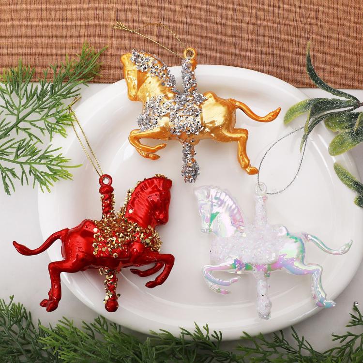 Three hanging rocking horse ornaments: red, gold, and white with glitter