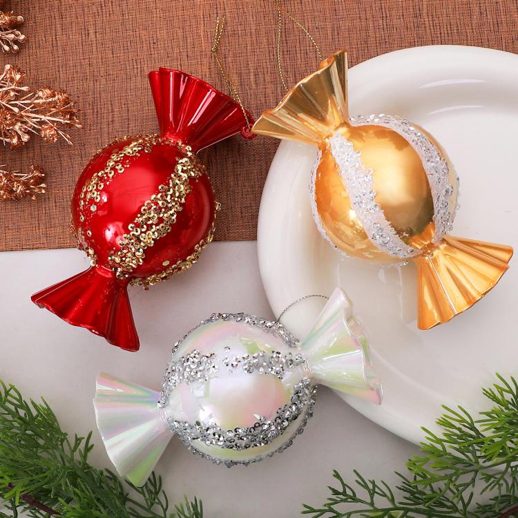 Candy-shaped Christmas ornaments in red, gold, and iridescent white on a display
