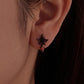 Gothic flower stud earring on ear, black petals with red enamel and amber teardrop dangle