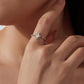 Moonstone ring on finger with oval pale center stone and small prong-set accents on band