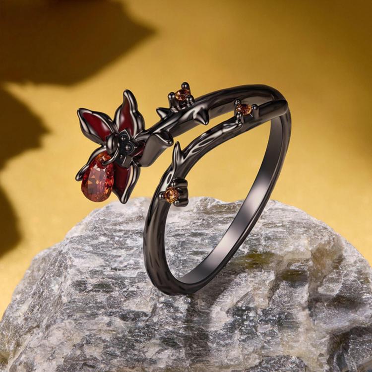 Open black ring with red bow flower motif and amber teardrop gem, top view