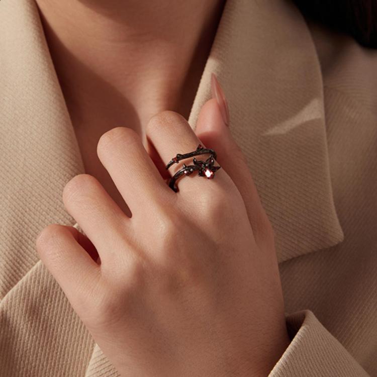 Open black gothic ring with red and amber gemstones on a person’s finger