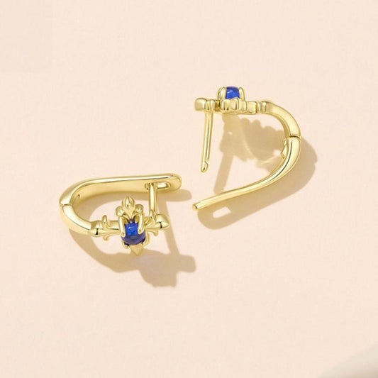 Gold-tone iris flower earrings with blue center and visible clasp, side view