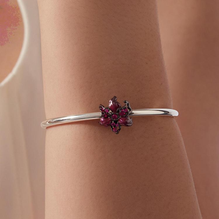 Silver bangle bracelet featuring a magenta devil flower charm with pink gemstone center