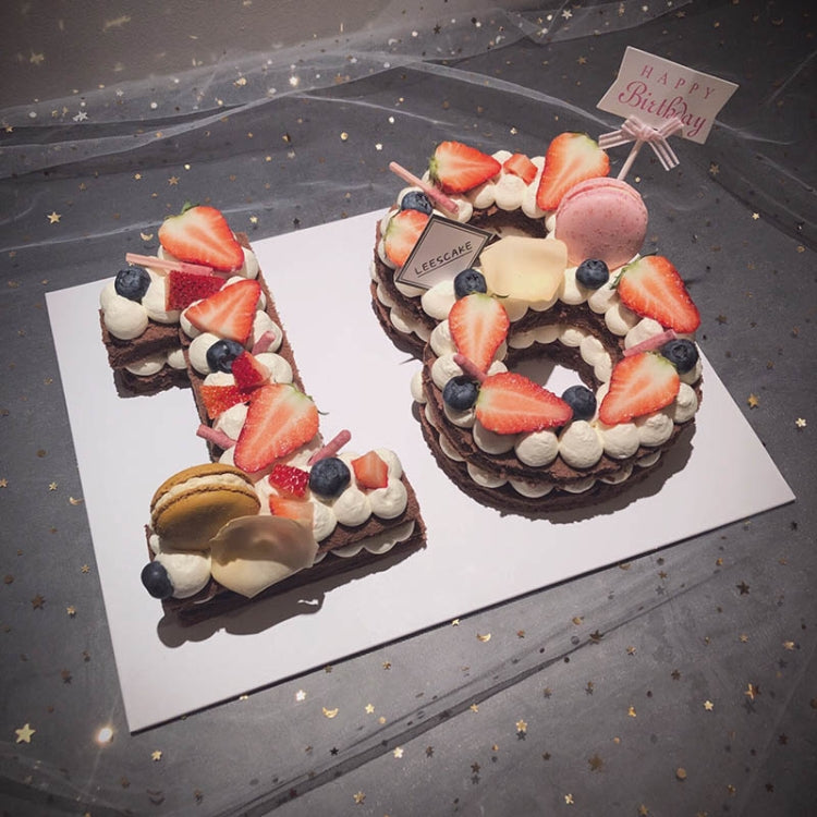 Two decorated number cakes with strawberries, blueberries, and whipped cream frosting