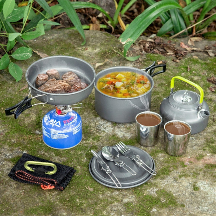 Camping teapot set for cooking: kettle, small pots, cups, and tools laid out