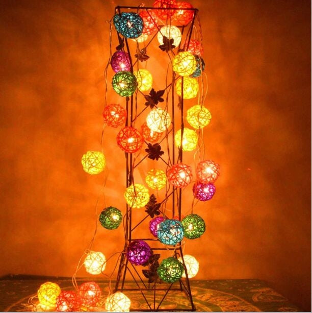 Multicolor LED rattan ball fairy lights on a tall black stand frame, glowing.