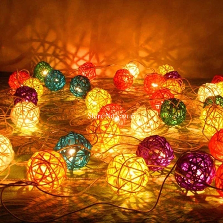 Colorful LED rattan ball string lights scattered on a surface, glowing.