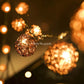 Glowing rattan ball LED fairy light close-up with softly lit background bulbs.