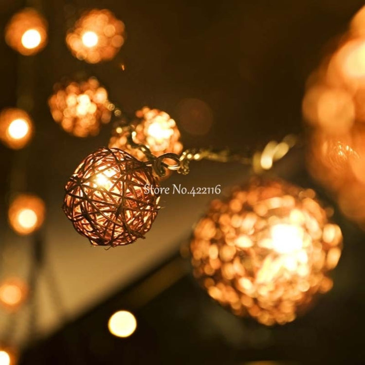 Glowing rattan ball LED fairy light close-up with softly lit background bulbs.