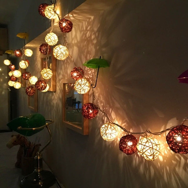Multicolor LED rattan ball fairy lights along a wall corner, glowing warm and red.