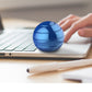Blue rotating tabletop ball gyroscope toy on a laptop keyboard with user hand nearby.